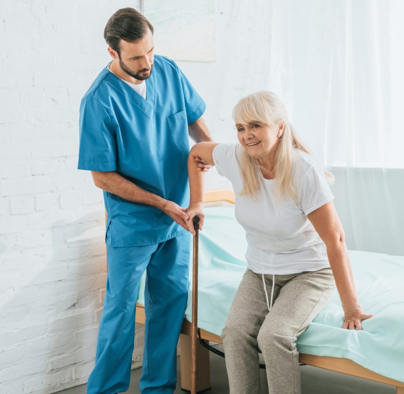 male-nurse-helping-senior-woman-with-walking-stick.jpg